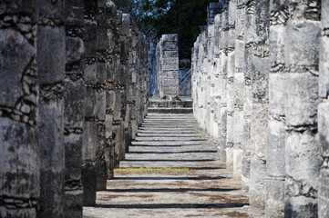 Ancient stone columns of Chichen Itza creating a historic pathway with shadows