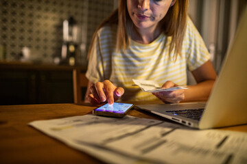 Woman feeling stressed while checking phone and working on laptop at night