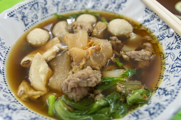 A vibrant bowl of savory broth filled with tender meat, vegetables, and dumplings, perfect for a comforting meal experience.