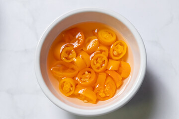 Yellow pickled chili in vinegar with copy space on background. Top view