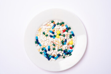 A lot of Assorted pharmaceutical pills and colorful capsules on a white plate. Different pills with selective focus.
