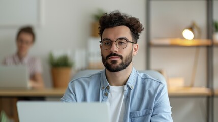 Fototapeta premium Thoughtful young man working on a laptop in a shared modern office space