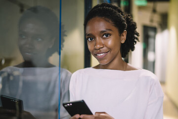 Sensual black lady browsing mobile at workplace