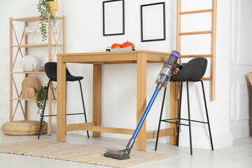 One cordless vacuum cleaner leaning on stool indoors