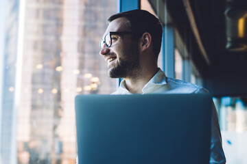 Businessman looking at window while using laptop