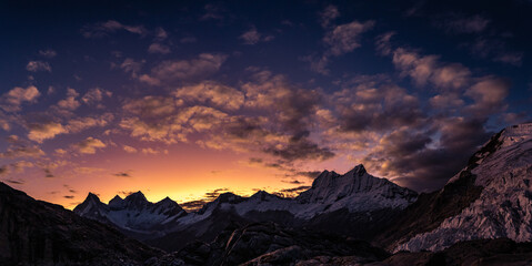 amazing sunset panorama over snowy mountain range with big glaciers with red, orange, violet and moonlight colors