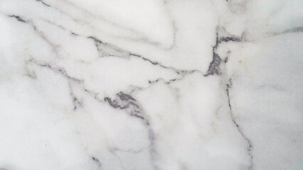 A close-up of a white marble surface with intricate gray veining. The natural patterns and textures create a luxurious and elegant aesthetic.