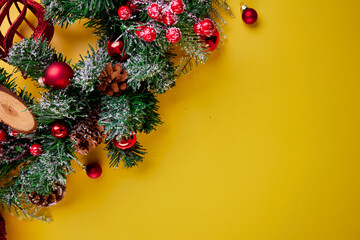A colorful close-up of lush green pine branches with striking red berries and delightful pine cones, all set against a bright yellow background, ideal for holiday themes and seasonal design ideas.
