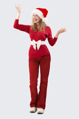 Merry Christmas! Beautiful, happy smiling young blonde woman playfully holding her arms open and looking at the camera. She is wearing a Santa hat, isolated against a white background