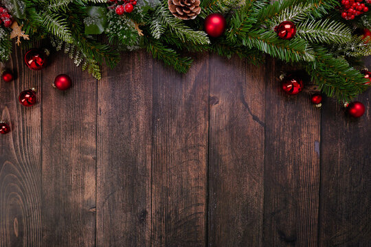  This beautiful rustic Christmas backdrop features a charming display of bright red ornaments and rich pine branches against a textured dark wood background, perfect for festive-themed designs. 