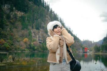 Happy travel girl standing by the mountain lake and looking at  view in autumn at Dagu Glacier Park , China.People with landscape concept.