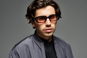 A young, handsome man showcases his trendy autumn outfit while confidently posing in a studio setting.