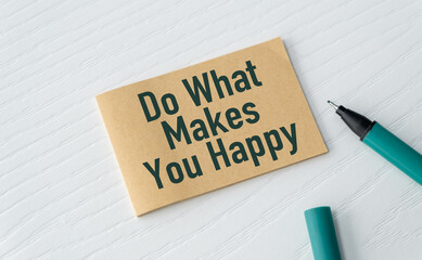 A piece of paper with the words Do What Makes you Happy written on it. A pen is sitting next to the paper