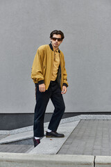 A stylish young man poses in a trendy autumn outfit, blending urban flair with seasonal charm.