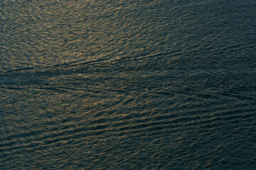 Aerial view of the dark blue ocean with textured water patterns and light reflections. Ocean wave background.