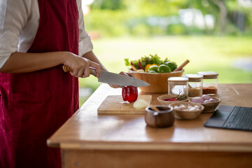 Woman in red apron cutting vegetables on wooden table