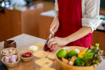 Woman in red apron cutting vegetables in a kitchen