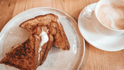 Delicious toasted bread on a plate close-up next to a cappuccino cup