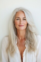 Fototapeta premium Confident mature woman with long gray hair smiling in white shirt