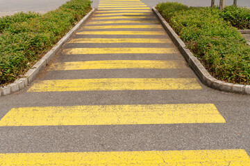 Long yellow pedestrian crossing symbol on the street.