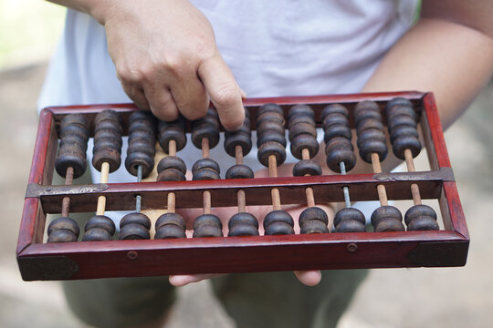 Close up man hand calculate and count wooden abacus. Concept, ancient style calculation. Counting equipment. Calculator. Educational material. Math teaching aid             