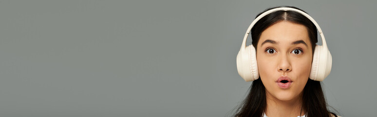 A young woman showcases her surprise in fashionable attire while enjoying music through headphones.