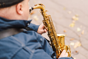 Naklejka premium A saxophonist performs in a serene park during autumn while seated on a bench surrounded by fallen leaves