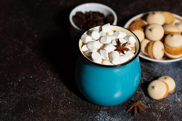 blue mug of spicy hot chocolate with marshmallows on dark background, closeup top view