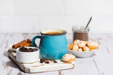 blue mug with hot chocolate and cookies on white table