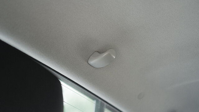 a small, plastic handle attached to the ceiling of a vehicle. The handle is designed to help passengers get in and out of the vehicle, especially in tight spaces.