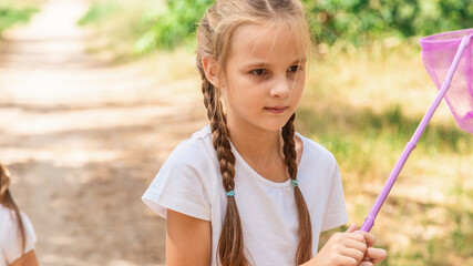 A child catches a butterfly in the park. Summer activity, nature.