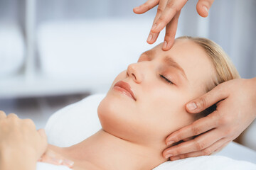 Fototapeta premium Caucasian woman enjoying relaxing anti-stress head massage and pampering facial beauty skin recreation leisure in dayspa modern light ambient at luxury resort or hotel spa salon. Quiescent
