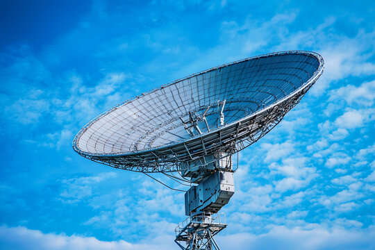 Large satellite dish overlooking a bright blue sky under sunlight