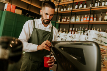 A barista skillfully prepares beverages in a stylish cafe, surrounded by an elegant display of glassware and rich colors
