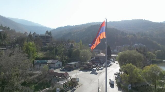 Arminian flag waving against a background of a road and green mountains in Dilijan, Tavush