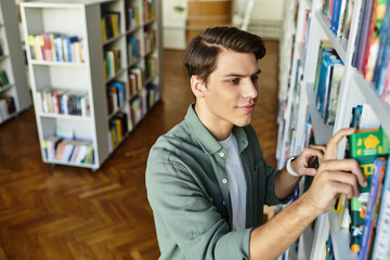A focused student meticulously arranges books on shelves in a university library setting.