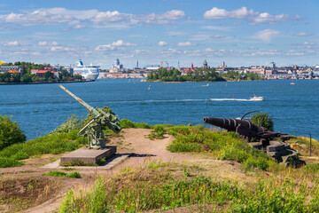 Cannons on island Lansi Mustasaari, Suomenlinna sea fortress with Helsinki city center in...