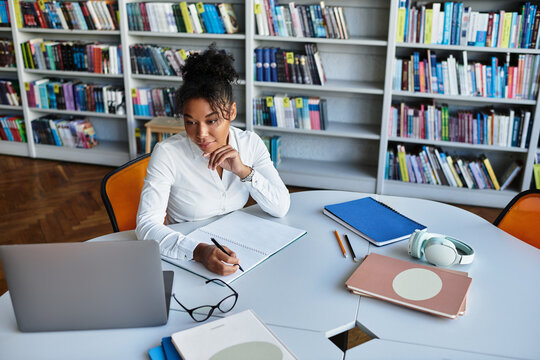 A dedicated teacher interacts with students while immersed in a lively library atmosphere.