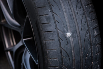 Fototapeta premium The tire was punctured by a nail and became flat, making it impossible to drive the car further because it could cause more noise from the tire. Therefore, it needs to be repaired first.