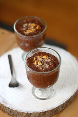 Two bowls of chia seed, chocolate and orange pudding. Healthy snack, wooden background. Selective focus.