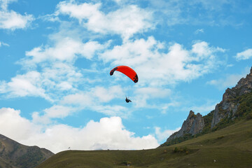 A lone paraglider in goraz against a cloudy sky towards the cliffs. Copy space.