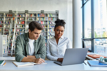 A dedicated teacher assists her student with learning in a bright, contemporary classroom.