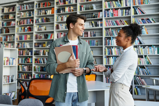 In a vibrant library, a teacher interacts with her attentive student, fostering learning and growth.