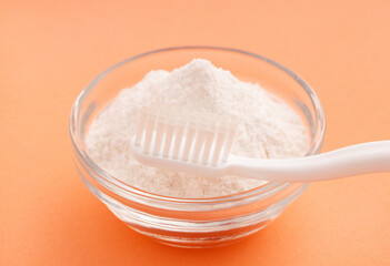 Toothbrush and baking soda in bowl - Pink background.