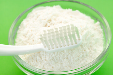 Toothbrush and baking soda in bowl - Green background.