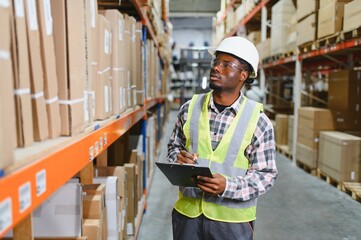 African american warehouseman with clipboard checking delivery, stock in warehouse