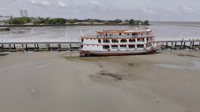 Drone flies over boats sitting on riverbed of Amazon River at low tide in Macap&aacute;, Amap&aacute;, Brazil