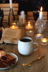 Books, lit candles, red wine, snacks and various deocration on the table. Dark academia or Halloween concept. Selective focus.