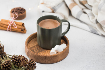 Hot chocolate mug and small marshmallows on wooden saucer