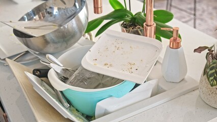 Kitchen Sink Full of Dirty Dishes Plate Drinking Glass Cutlery and Cutting Board